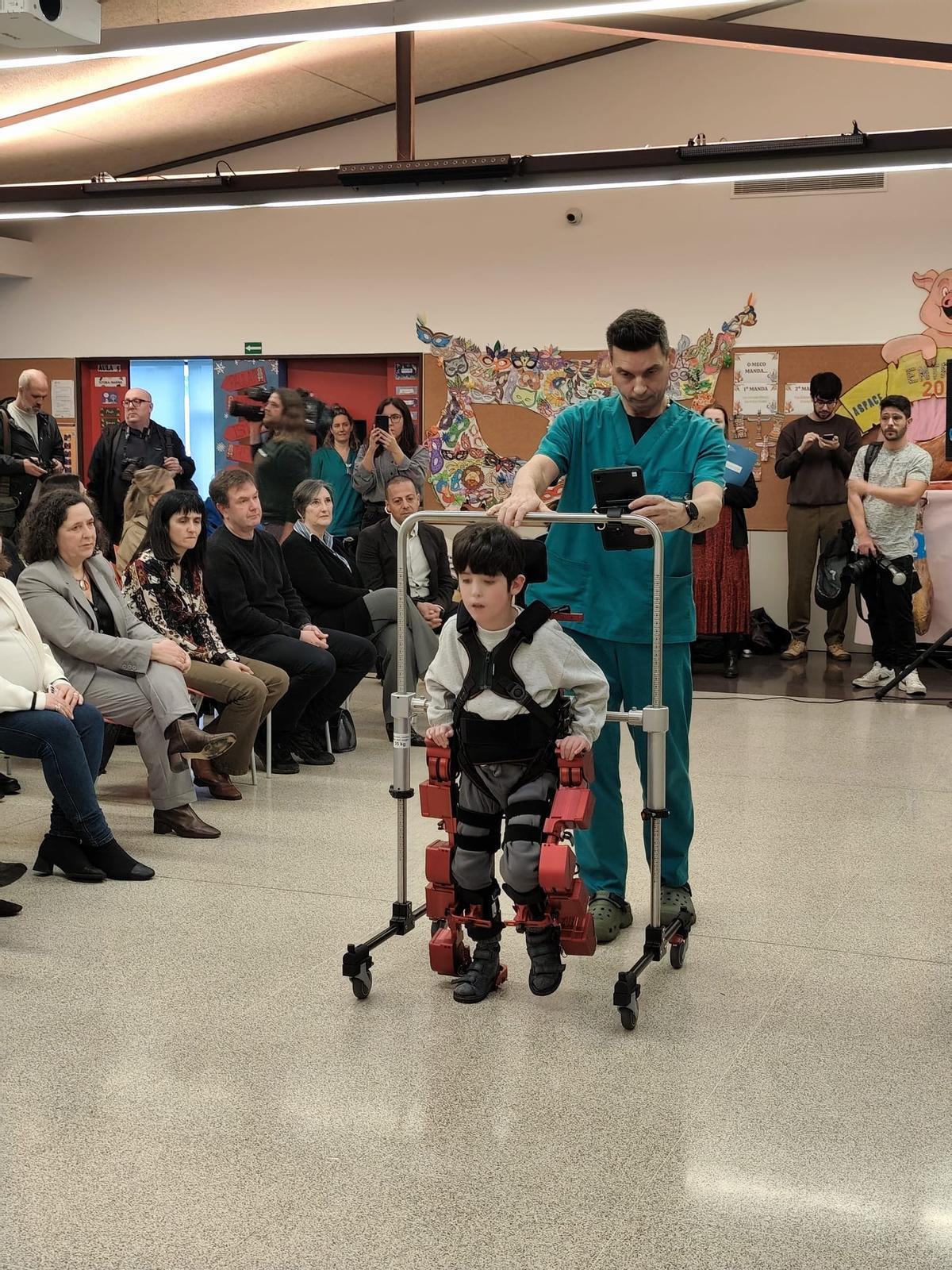 El pequeño Darío da unos pasos asistidos con el exoesqueleto, con la ayuda del fisioterapeuta Santiago Carral, este miércolesm en las instalaciones de Aspace Coruña.