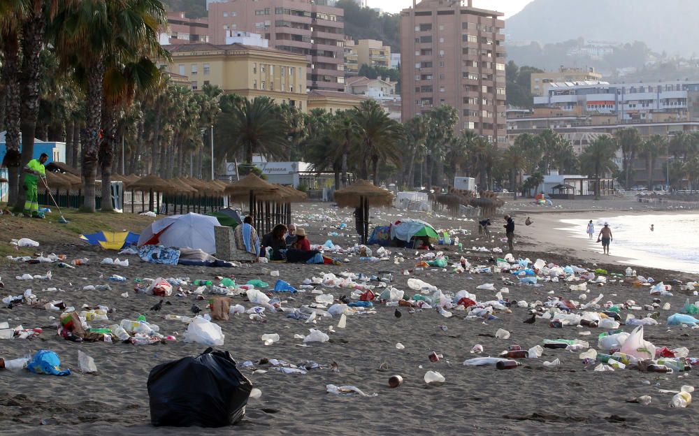 Los operarios de los servicios de limpieza trabajan para dejar la playa en óptimas condiciones tras una larga noche de fiesta en la arena