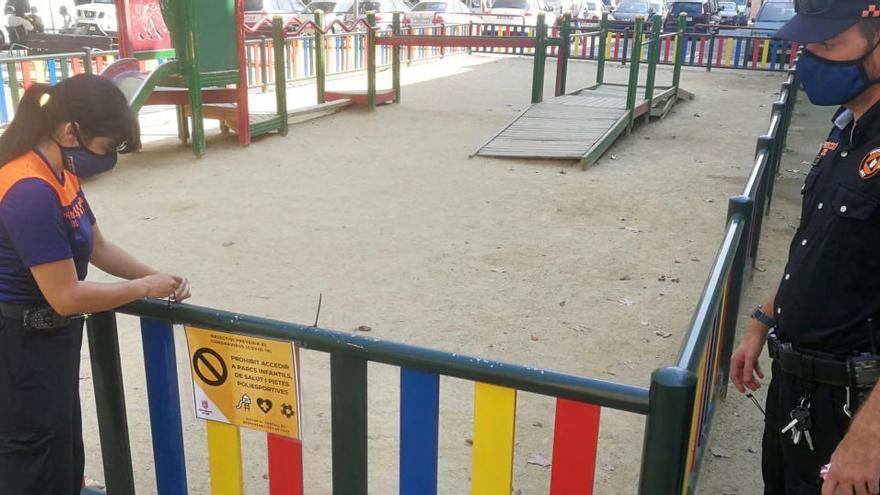 Dos voluntaris de Protecció Civil posant una cinta en un parc infantil