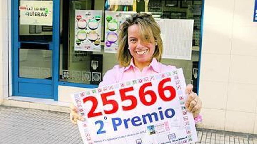 Elisabeth Roces, ante su administración de lotería, con el cartel del premio.