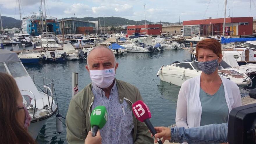 Joan Torres y Lucía Ribas, ayer, frente a uno de los barcos de las navieras  que su partido quiere que no atraquen más en el puerto de Sant Antoni.