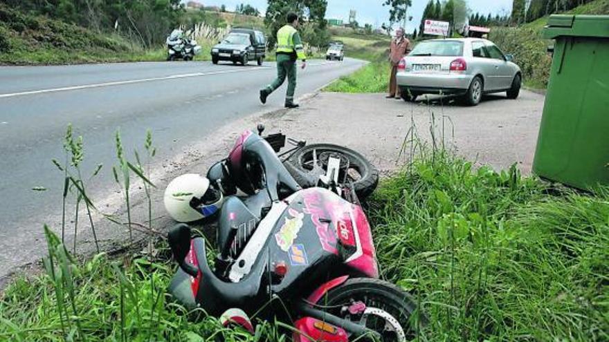 En primer término, la moto implicada en el choque; detrás, un guardia civil en el lugar del accidente.