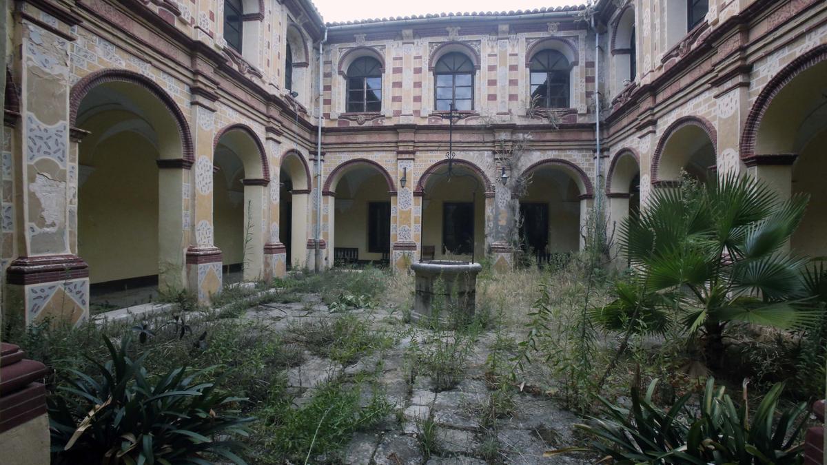 El patio porticado del monasterio lleno de maleza.