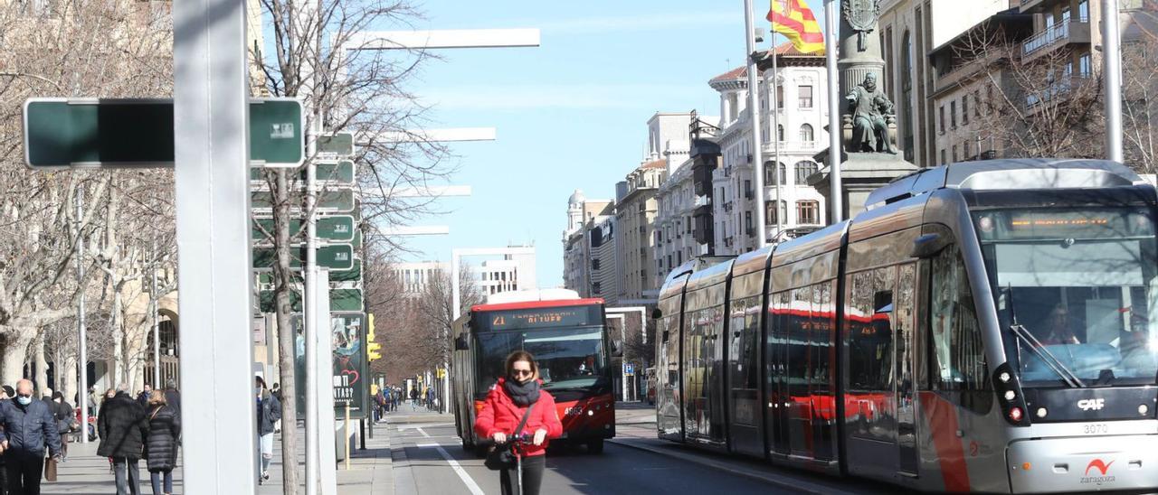 Una usuaria de patinete saca distancia a un autobús y el tranvía en el paseo Independencia de Zaragoza.  | ÁNGEL DE CASTRO