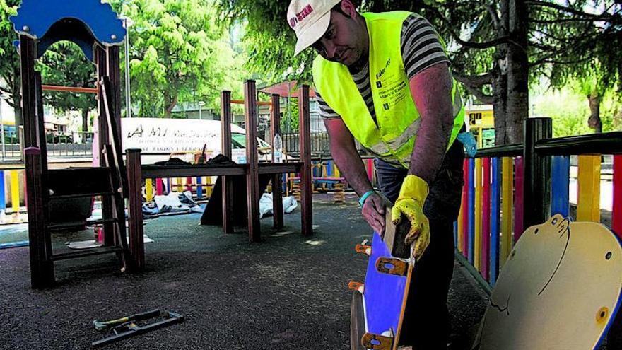 Un operario municipal retira elementos de juego en el parque de Praza da Vila.