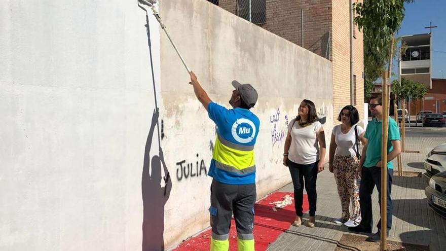 Un operario elimina una pintada de un muro en Los Rosales.