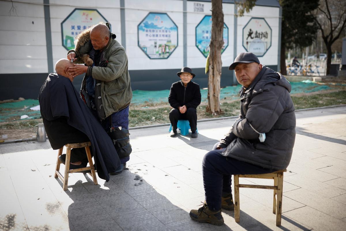 Un peluquero callejero afeita la cabeza de un cliente mientras China regresa al trabajo a pesar de los continuos brotes de la enfermedad por coronavirus (COVID-19) en Beijing.