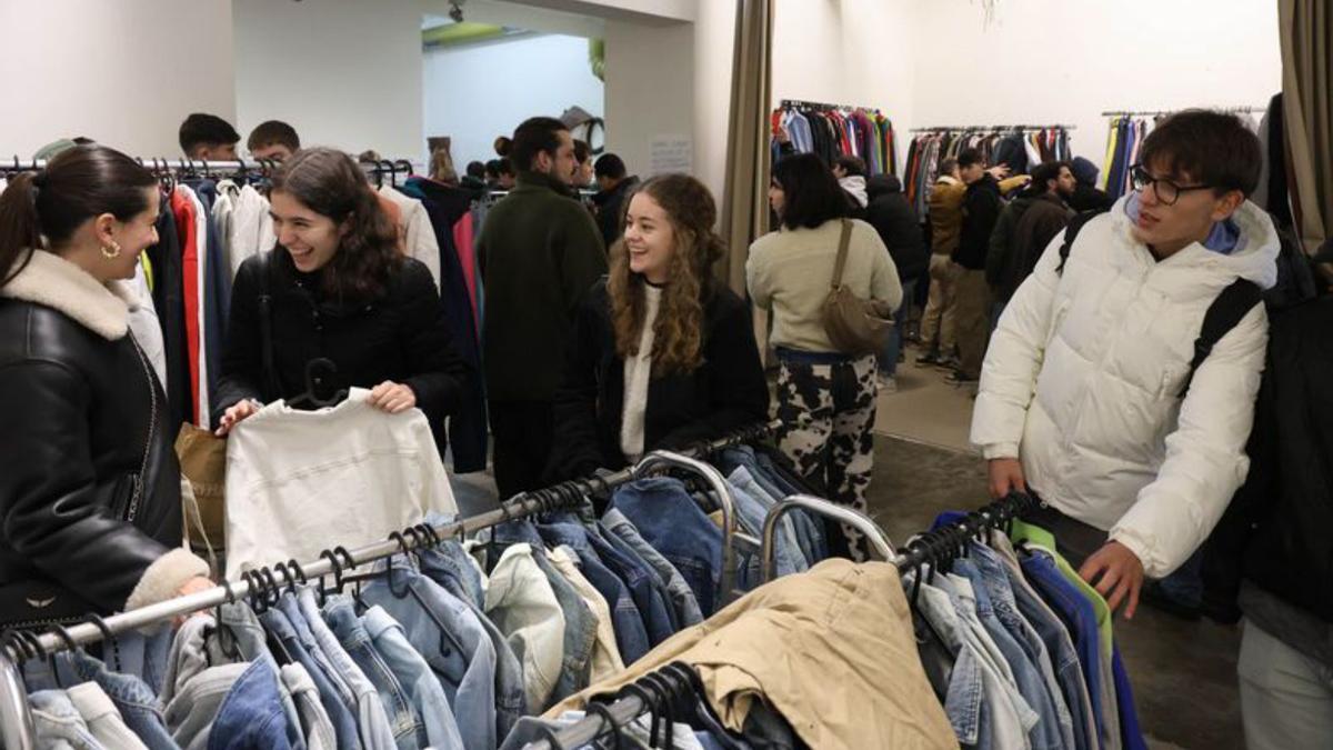 Un grupo de jóvenes revisa las prendas del mercadillo.