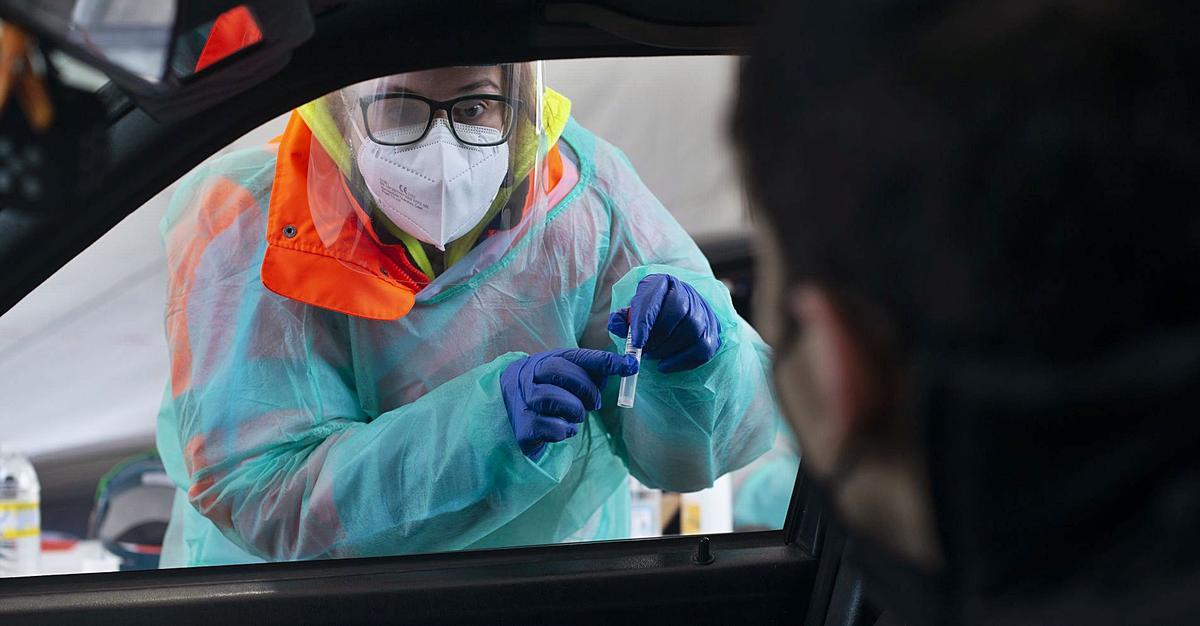 Una sanitaria explica a un hombre en Verín cómo recoger la muestra de saliva para la prueba.   | // BRAIS LORENZO