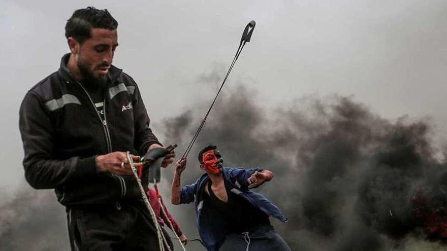 Manifestantes palestinos lanzan piedras con sus ondas contra las posiciones del Ejército israelí. // Efe