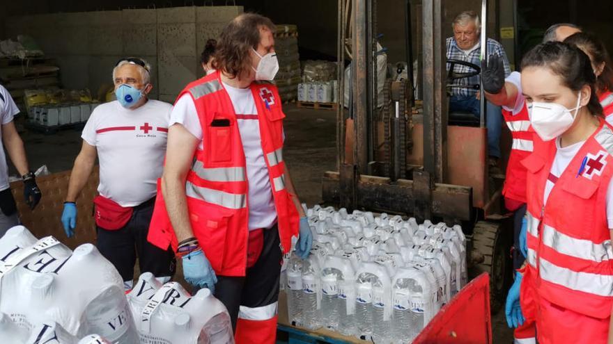 Voluntaris de la Creu Roja carregant ampolles d&#039;aigua per repartir-los als veïns de quatre municipis.