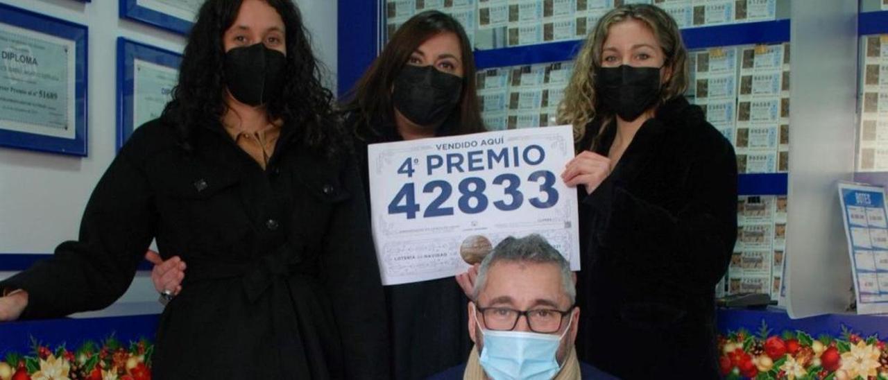 Virginia González, Paloma Ania, Irene Valdés y Joaquín González, ayer, en la administración de loterías de Llanes, con carteles del cuarto premio del Gordo de Navidad, vendido allí. | Ramón Díaz