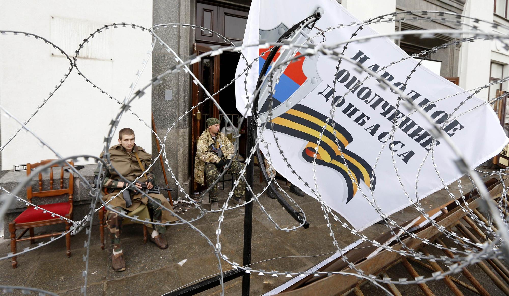 Milicianos prorrusos sentados a la entrada de la sede del Gobierno de la región de Lugansk en una foto de archivo
