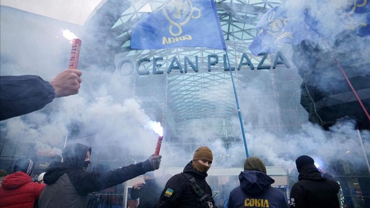 Simpatizantes ucranianos de ultraderecha queman bengalas en Kiev mientras bloquean el acceso al centro comercial Ocean Plaza, del oligarca ruso Boris Rotenberg, una figura cercana a Vladimir Putin.