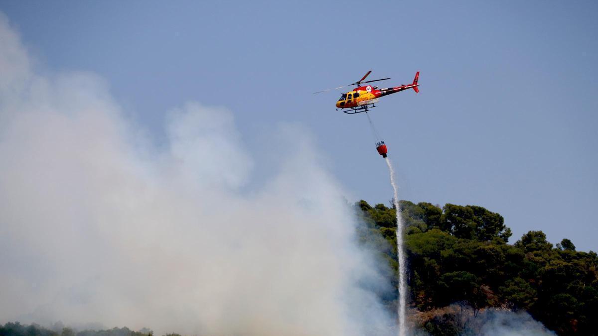 Un helicòpter descarrega aigua en un incendi forestal a Alforja