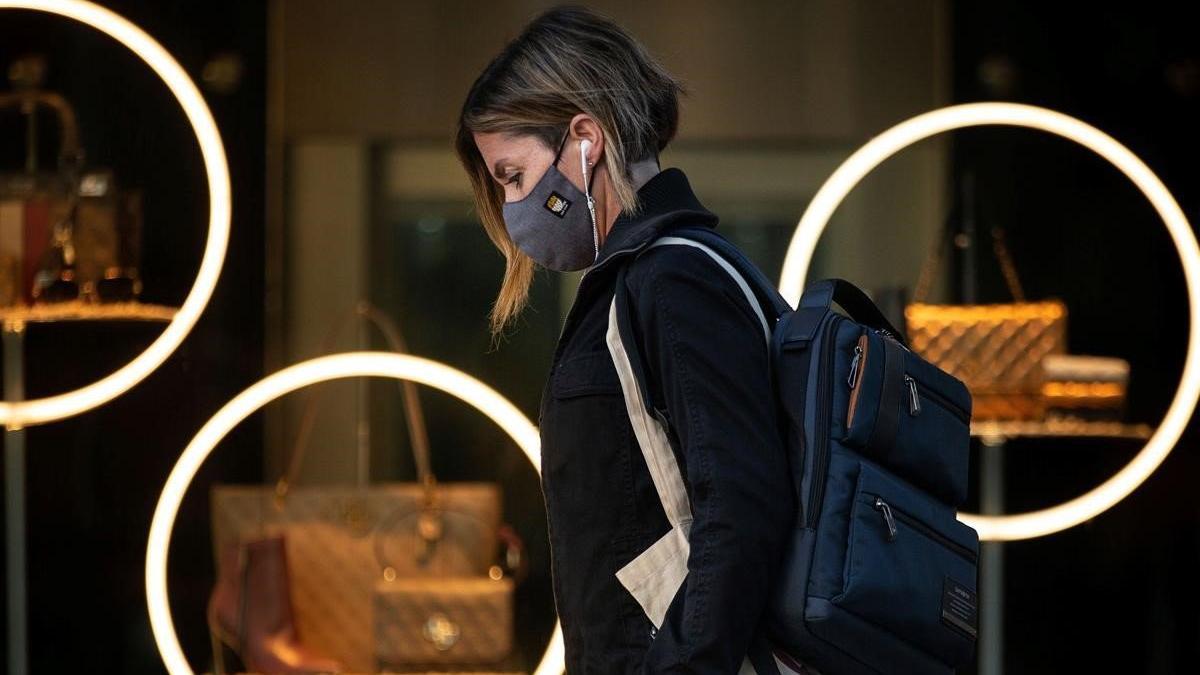 Una mujer protegida con una mascarilla camina por el paseo de Gràcia de Barcelona.