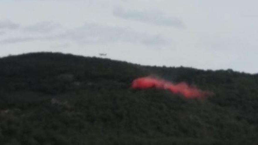 Una avioneta llença líquid retardant sobre el foc.