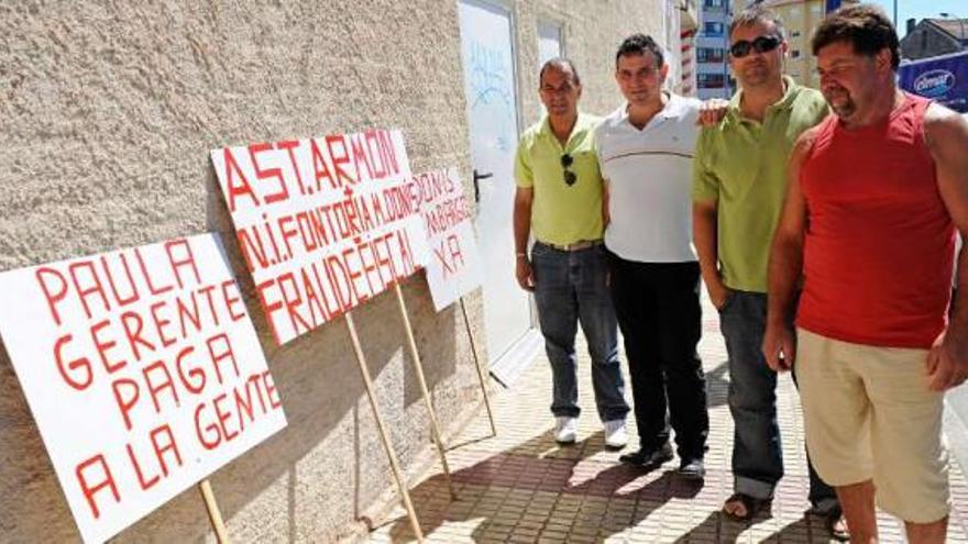 Extrabajadores de la empresa de Culleredo, junto a pancartas en que reivindican su dinero. / 13fotos