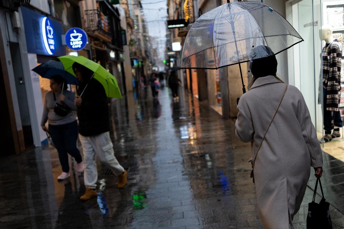 Ciudadanos se protegen de la lluvia con paraguas.