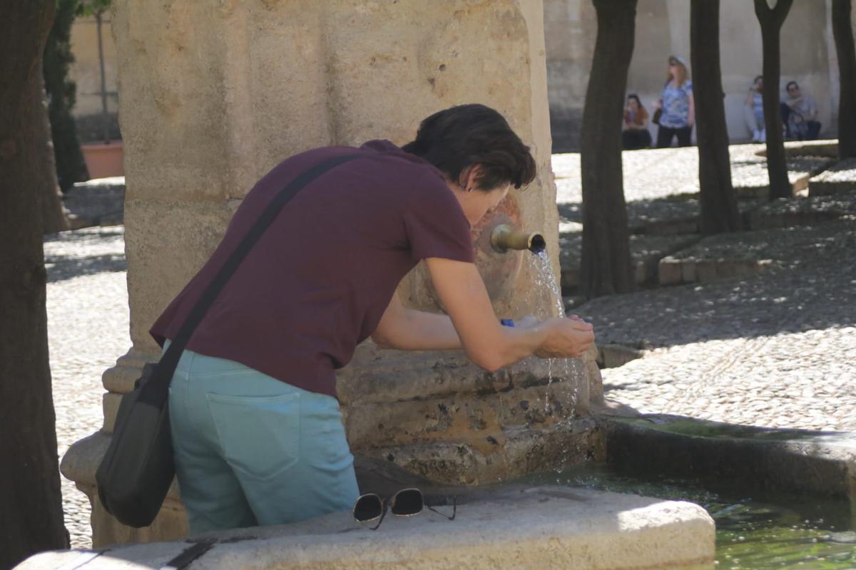 Una mujer busca refrescarse en una fuente ante el intenso calor.