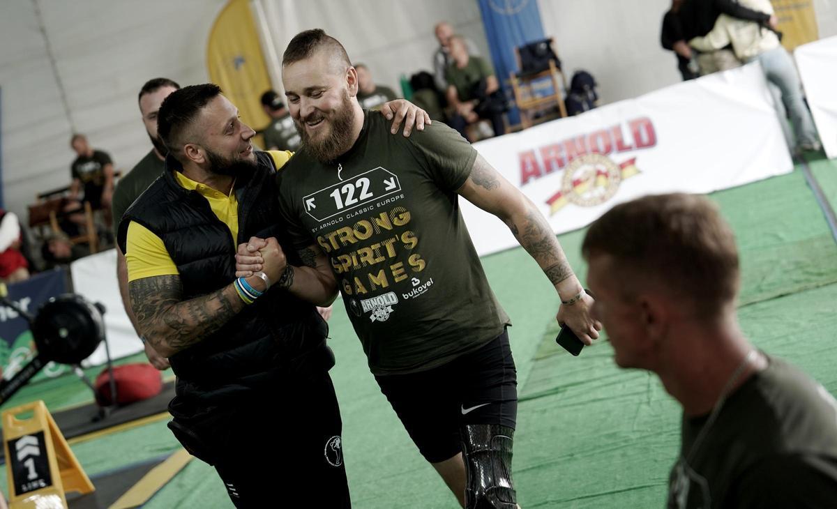 Un veterano de guerra ucraniano recibe el apoyo de su entrenador tras tomar parte en una prueba en el Strongman de Las Rozas (Madrid).