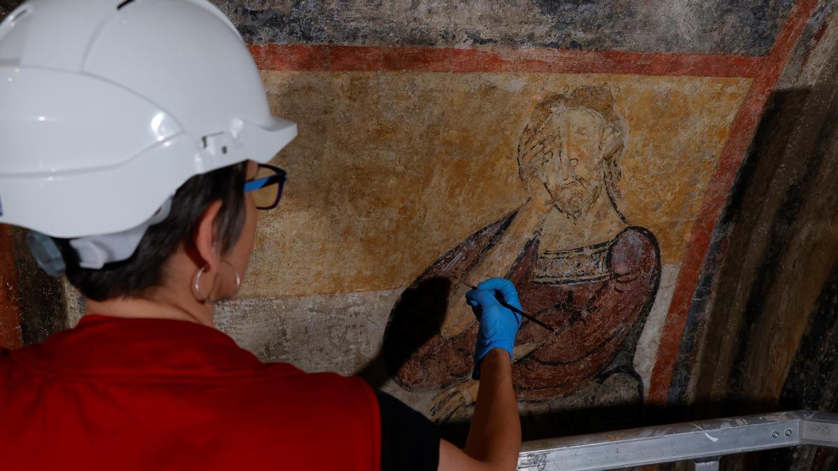 Una restauradora ultima los trabajos con la figura de Caín en el ábside de Sant Climent de Taüll, en el MNAC.