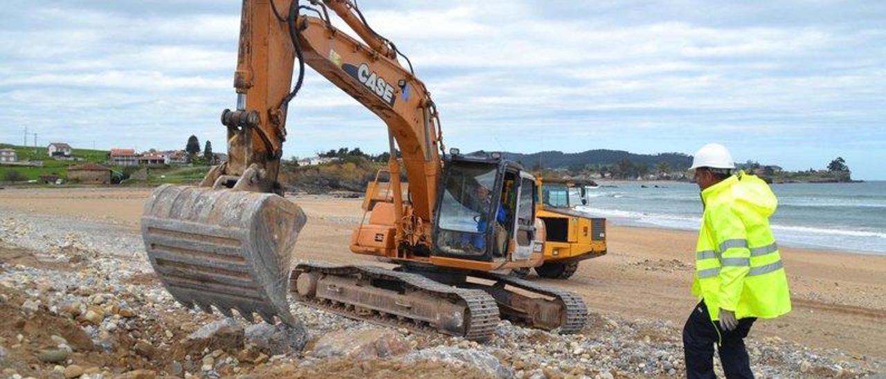 Dos operarios, en las labores de rehabilitación de la escollera de la playa de La Espasa.