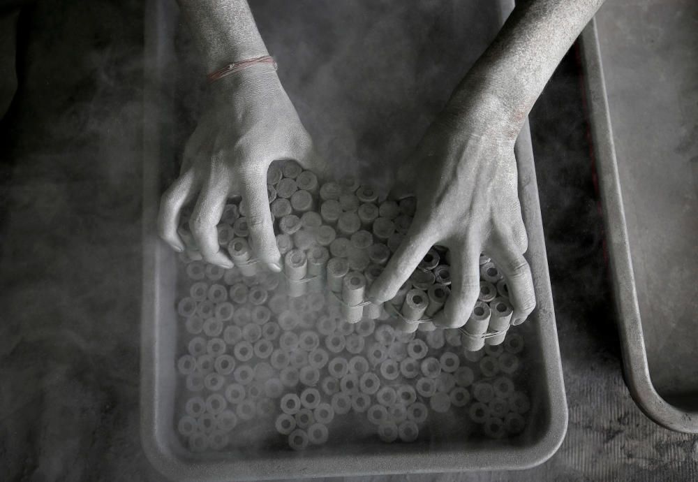 A worker removes paper rolls after filling them ...