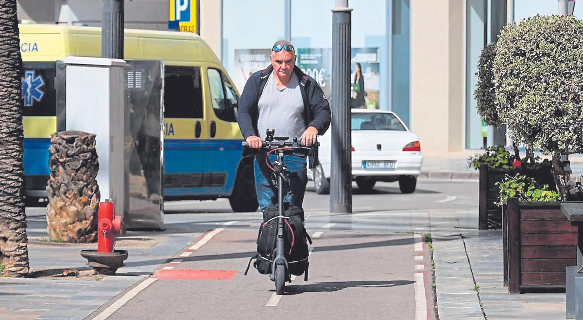 Un hombre circula con un patinete por una calle de cartagena.