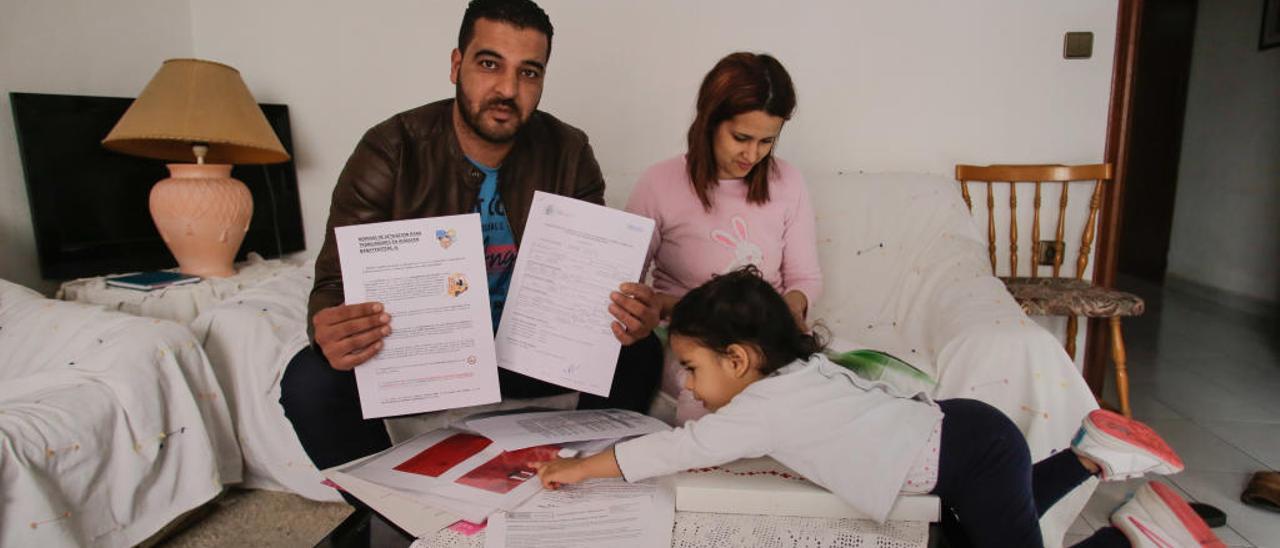 Abdelali muestra papeles del trabajo que tenía en una fábrica en una imagen en el domicilio que tiene alquilado en Elche en la que aparece su mujer, Meryem, y su hija.