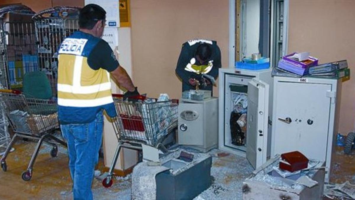 Un agente de la policía traslada con un carro de supermercado billetes de una de las cajas fuertes intervenidas en la operación Chequian-Emperador.