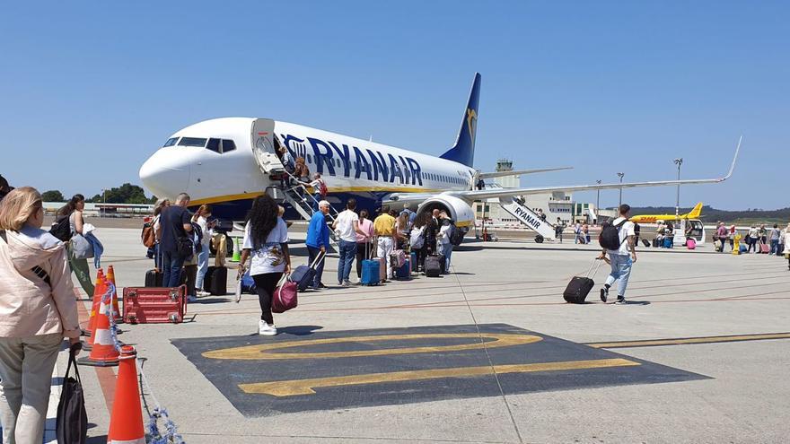 Varios pasajeros se disponen a subir a un avión de la compañía irlandesa Ryanair en la pista del aeropuerto Rosalía de Castro