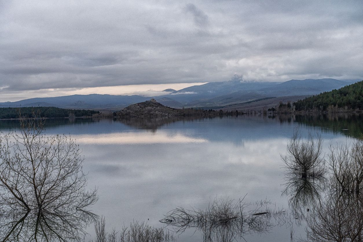 Las tranquilas aguas del embalse de Aguilar reflejan las nubes y las lejanas colinas.