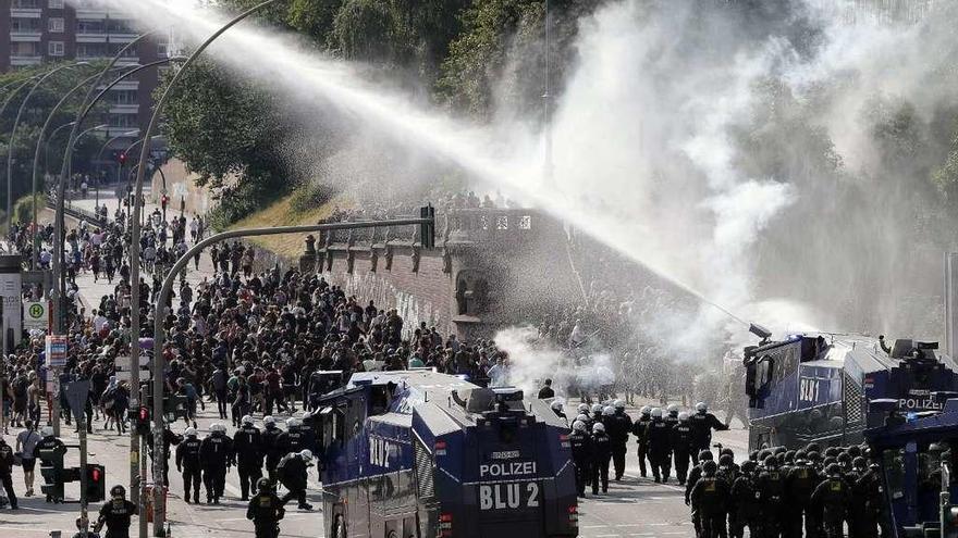 Policías antidisturbios dispersan con cañones de agua a manifestantes en una vía de Hamburgo. // Efe