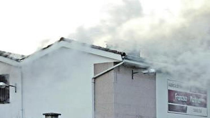 Unos bomberos, sofocando el fuego en el secadero de embutidos, ayer, en Nava.