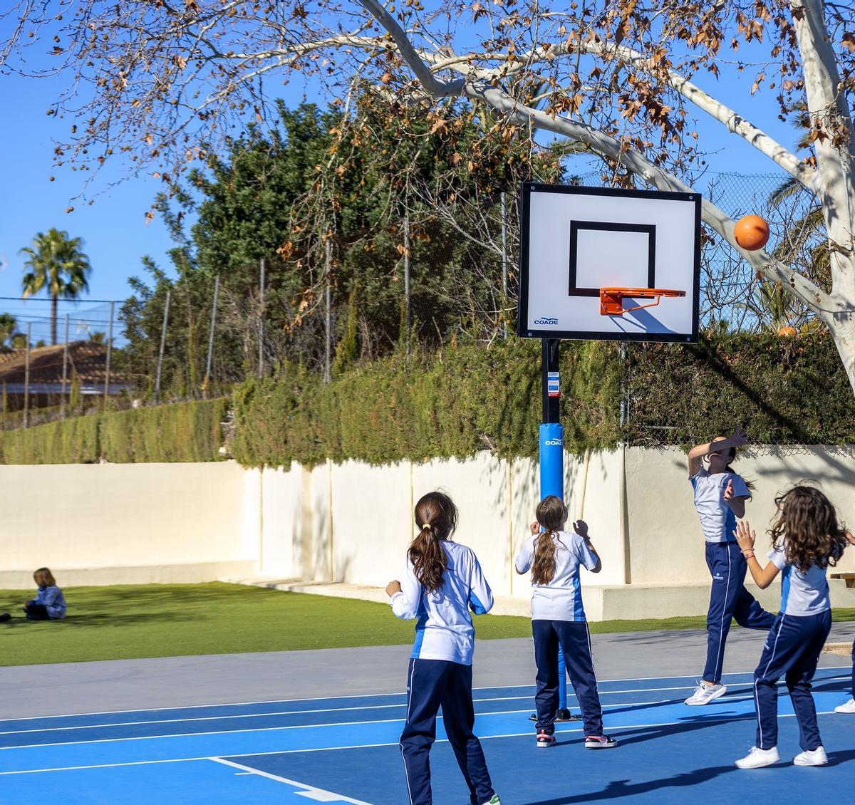 Un grupo de alumnas disputan un partido de baloncesto en el patio del centro escolar.