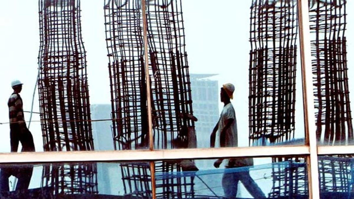 Dos obrers indonesis es reflecteixen sobre la finestra d’un edifici en ple centre financer de Jakarta.