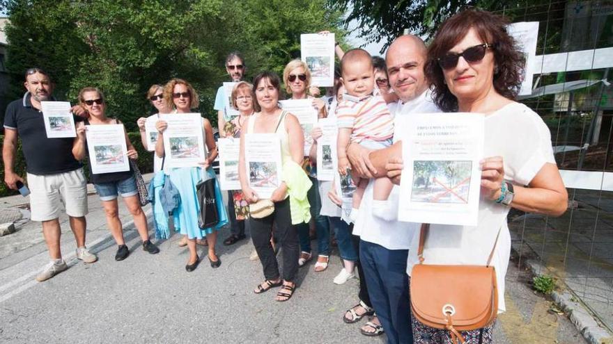 Un grupo de vecinos en los terrenos del viejo hospital, con los carteles que convocan para hoy a las doce a una acción reivindicativa de &quot;okupación&quot; de los terrenos.