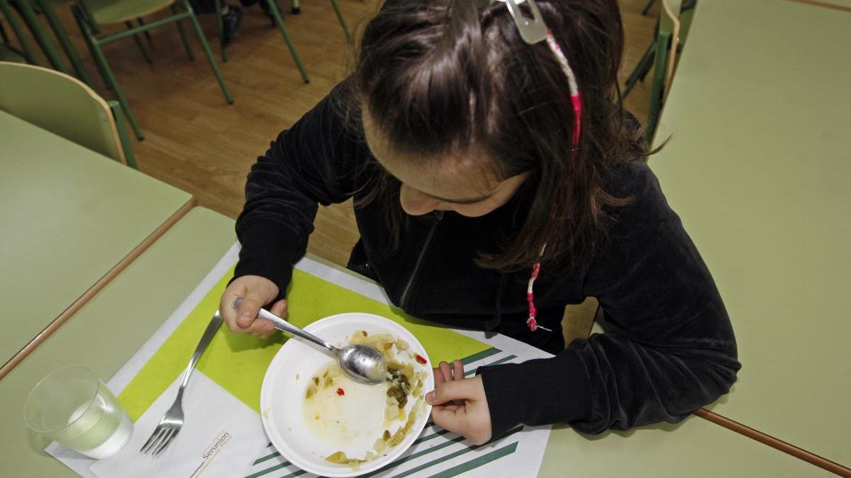 Una niña almuerza en el comedor en escolar. // M.G.Brea