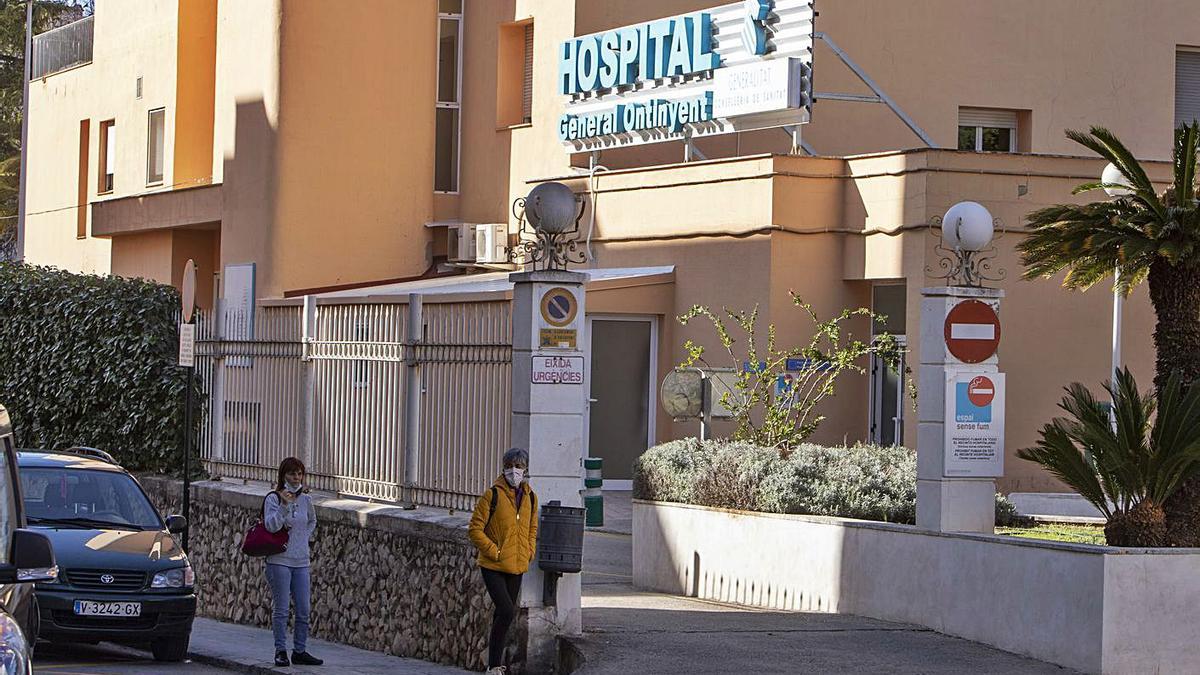 Dos viandantes caminan ante el Hospital de Ontinyent, en una imagen de esta semana. | PERALES IBORRA