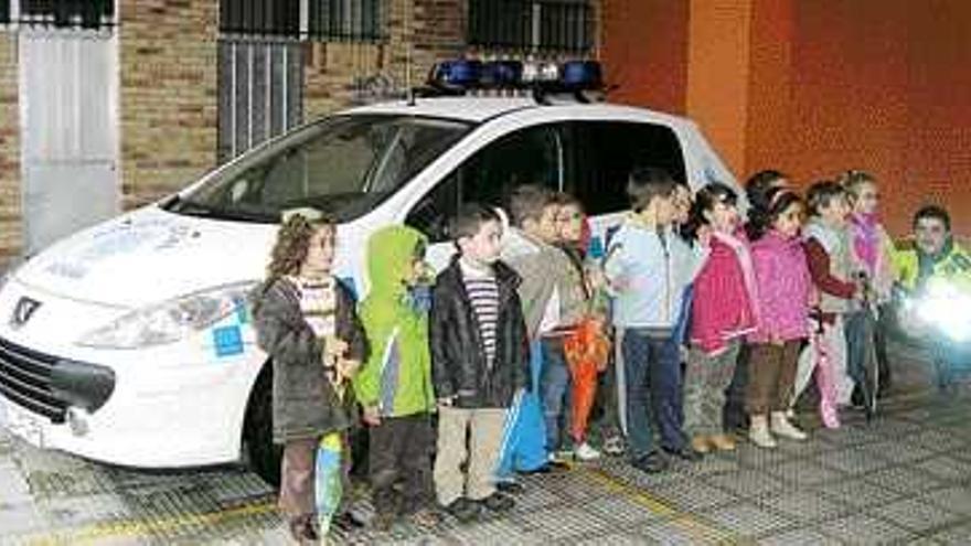 Un grupo de alumnos posa delante del coche de la Policía y junto a un agente. / gonzalo nÚñez