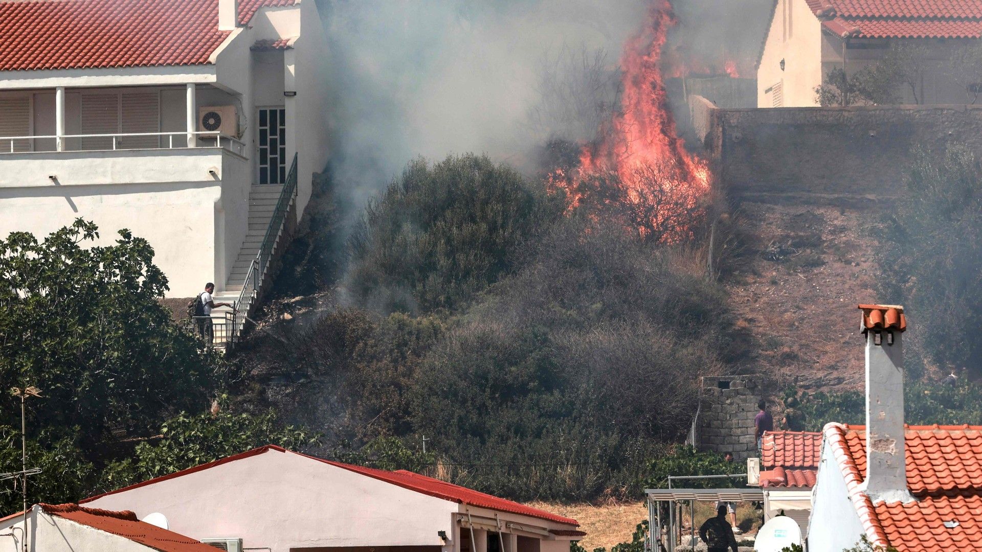 Varias personas miran el avance de las llamas en la isla griega de Lesbos, este sábado