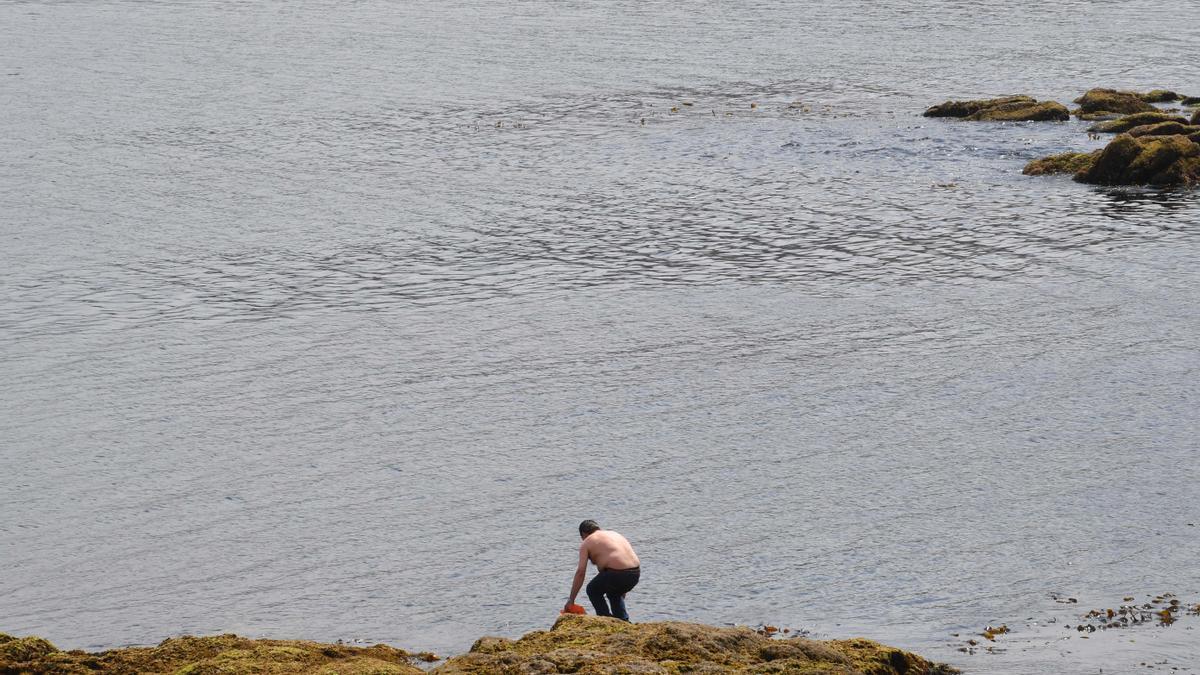 Un hombre en las rocas de la playa coruñesa de Riazor este verano.