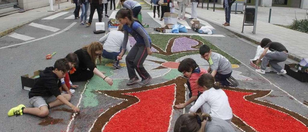 Un grupo de jóvenes trabaja en una alfombra en la calle Pazos Fontenla, en Bueu. // Santos Álvarez