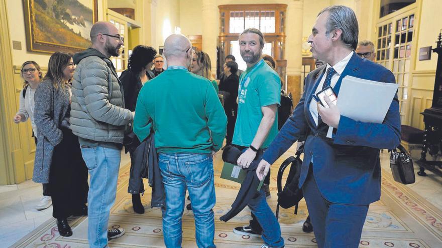El conseller Vera saluda a algunos asistentes a su comparecencia (varios con camisetas verdes) a su llegada al Parlament.  | G.BOSCH