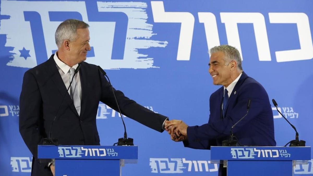 Benny Gantz (izquierda) y Yair Lapid se estrechan la mano mientras anuncian una declaración conjunta.