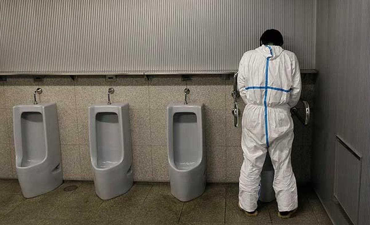 Un treballador encarregat de revisar la radiació utilitza un urinari en un lavabo del centre d’evacuació de Koriyama, a 70 km de la planta nuclear de Fukushima (Japó).