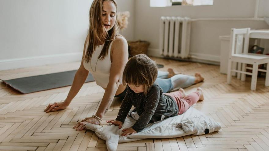 Una pequeña haciendo yoga con su madre