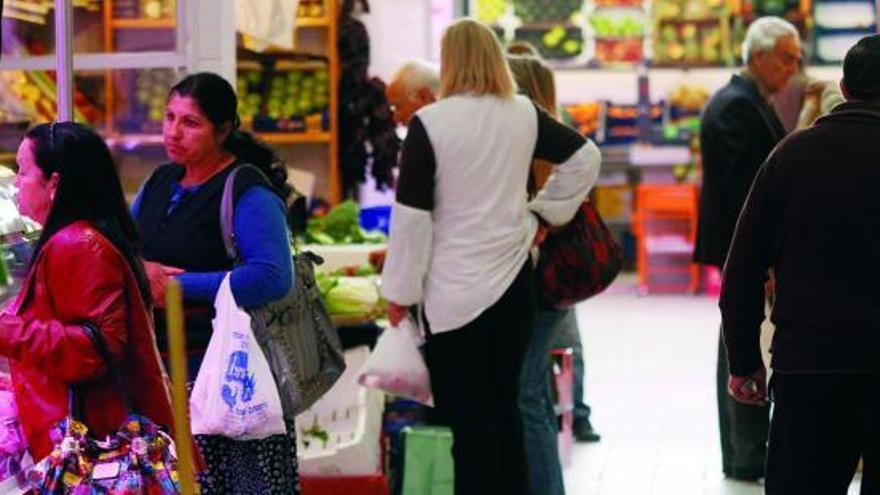 Varios clientes realizan sus compras en los puestos del Mercado de Abastos.