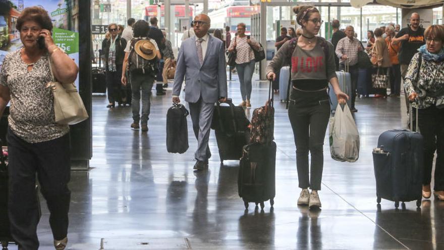 Pasajeros abandonan la estación de tren de Alicante con sus equipajes.